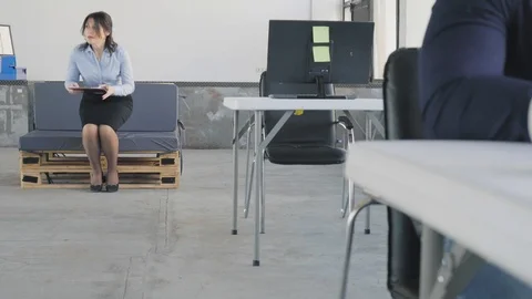 A female manager gets up from the couch, walks up to employees who sit at Stock Footage 109416329