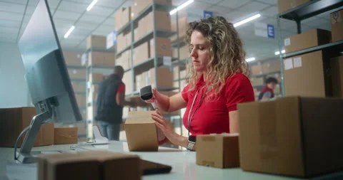 Female manager scans parcel using barcode scanner, enters data on computer Stock Footage 307557696