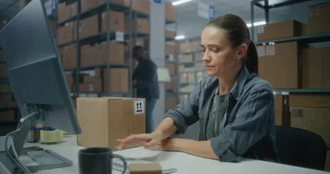 Female manager scans parcel using barcode scanner, enters data on computer 스톡 동영상 307617304