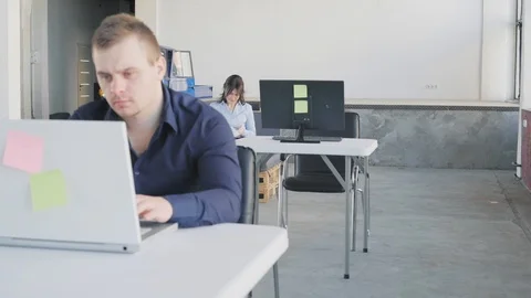 A female manager sits on a sofa, gets up, passes by an employee who sits at a Stock Footage 109376349