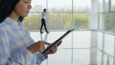 Female manager standing in empty office with tablet computer Stock Footage 125707317