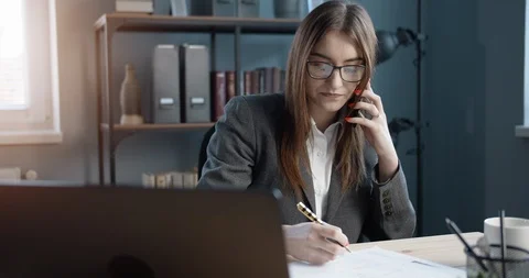 Female manager taking notes during conversation on phone Stock Footage 123561250