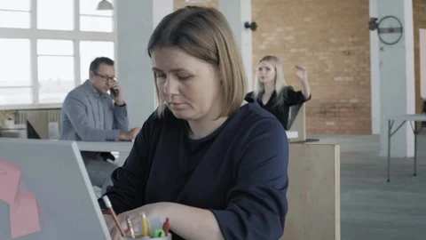 Female manager is working in office, sitting at desk, with laptop. A group of Stock Footage 124705722