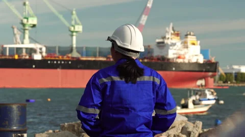 Female maritime engineer in blue uniform and hard hat watching cargo ship Video stock 342919751