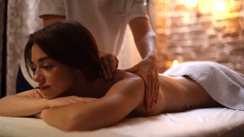 Female masseuse does shoulder and back massage to young woman in spa centre Stock Footage 125986570