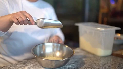 Female master adding flour to metal bowl with eggs Stock Footage 239512600