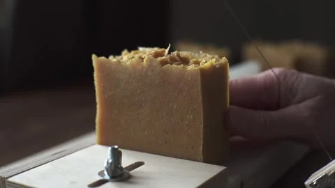 A female master soap maker cuts yellow sea buckthorn handmade soap Stock Footage 278301413
