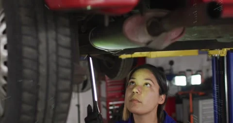 Female mechanic activating LED, inspecting muffler in garage while digital Stock Footage 330191148