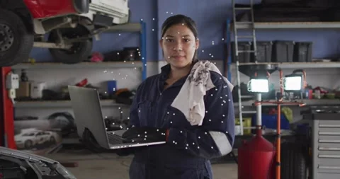 Female mechanic diagnosing engine, checking laptop in garage, looking down and Stock Footage 331084686