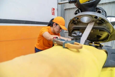 Female mechanic using digital multimeter checking motorcycle battery voltage Stock Photos
