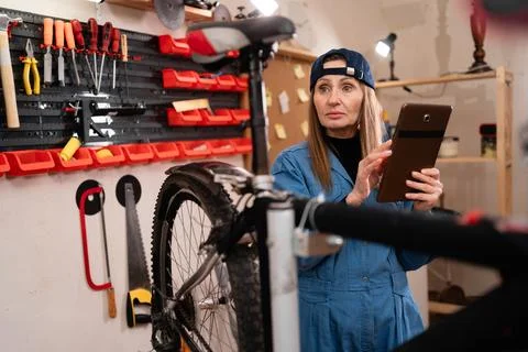 Female mechanic using a digital tablet for diagnostics in a bike workshop. Wo 스톡 사진