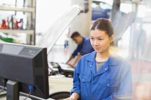 Female mechanic working at computer in auto repair shop Stock Photos