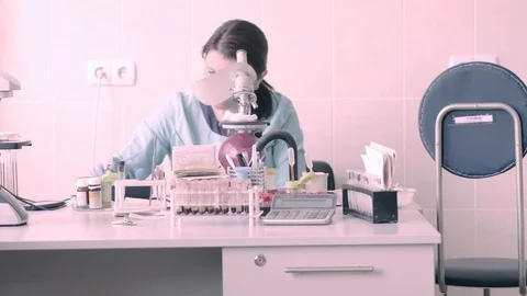 A female medic looks through a microscope, examines a man’s blood and Stock Footage 99511695