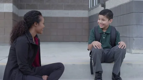 Female mentor talks to student after school outside school building Stock Footage 142025053