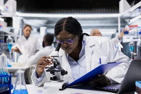 Female microscopist studying cellular structures through microscope lens Stock Photos