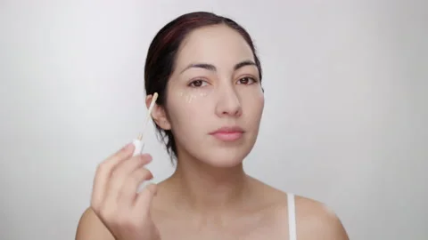Female model demonstrates application of concealer under eye, blends with brush Stock Footage 193591377
