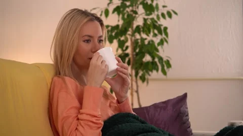 Female model drinking tea on sofa at home. Video stock 266462157