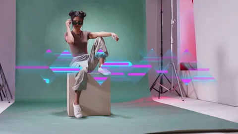 Female model grabbing sunglasses, posing on box for fashion photography, glitch Stock Footage 333004429