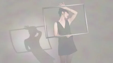 Female model holding rectangular frame and rotating it, shaping shadow for Stock Footage 334112776