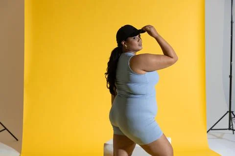Female model posing, adjusting black cap, wearing ribbed blue set in studio with Stock Photos