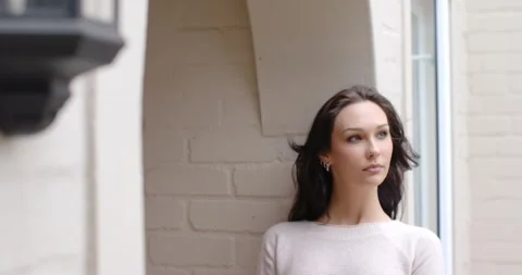 Female model posing by brick alcove near window, breeze lifting hair, turning Stock Footage 344405350