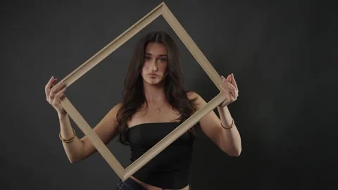 Female model posing with empty frame, beauty and self-expression concept, studio Stock Footage 336936755