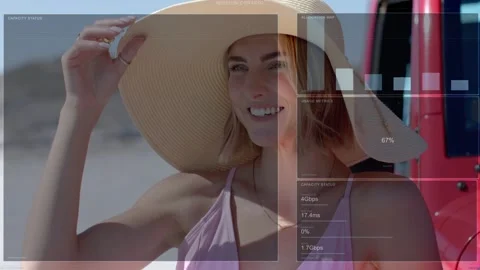 Female model raising right hand, adjusting hat on beach, activating HUD charts Video stock 333540281