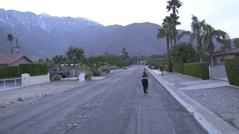 Female model running away from camera in sports bra and pants at dusk in desert Stock Footage 76722418