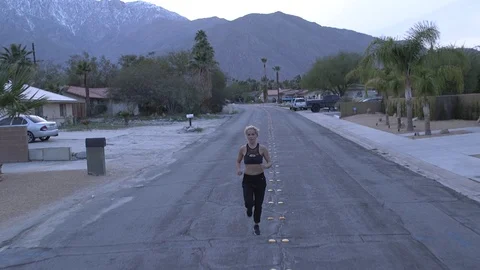 Female model running toward camera in sports bra and pants at dusk in desert 库存影片 76722411