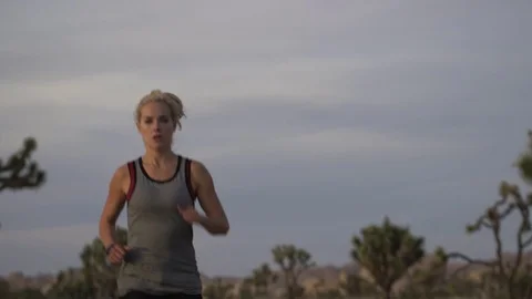 Female model running toward camera on desert road at sunset with cactus Stockbeeldmateriaal 76722682