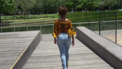 Female model walking across a bridge in the park Stock Footage 196358672