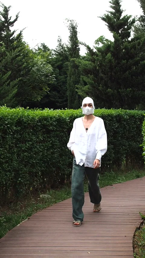 Female model in a white leather face mask walks the catwalk in city park Stock Footage 248528744