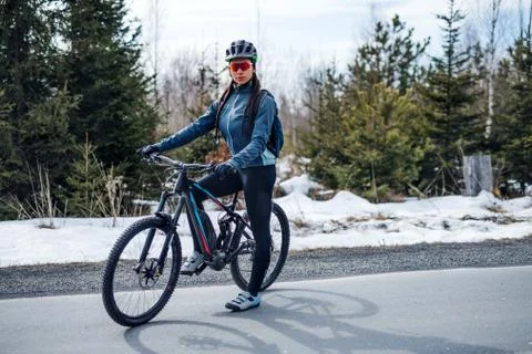 Female mountain biker standing on road outdoors in winter nature. Stock Photos