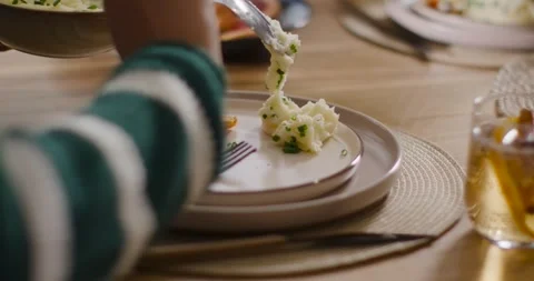 Female moving spoon into frame, scooping mashed potatoes onto plate for family Stock Footage 339268297