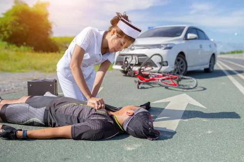 Female nurse helping emergency CPR to asia cyclist injured Stock Photos