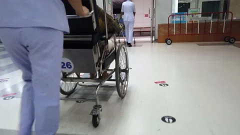Female nurse pushing wheelchair of patient through hospital walkway. Stock Footage