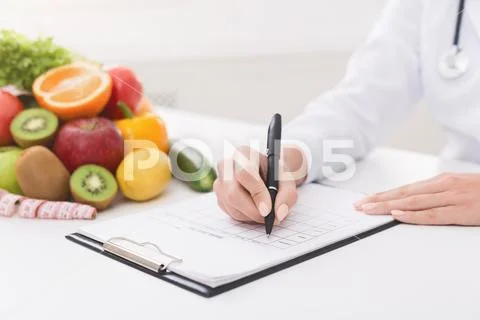 Female nutritionist doctor writing vegetable diet plan Stock Photos