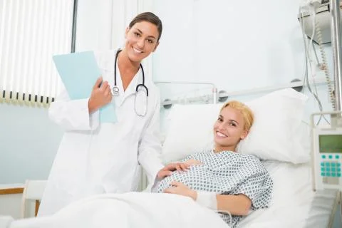 Female obstetrician talking to a smiling pregnant woman Stock Photos