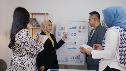 Female office worker talking and pointing at a graph and chart information .. Stock Footage 344090921