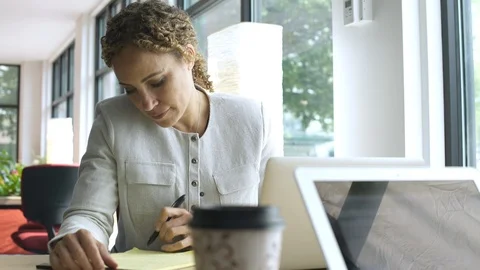 Female office worker writing on notepad, smiling at camera. 動画素材 88027015