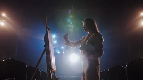Female painter creating artwork under dramatic cinematic lighting Stock Footage 337505377