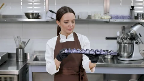 Female pastry chef in a professional kitchen holds handmade chocolates. Stock Footage 170103467