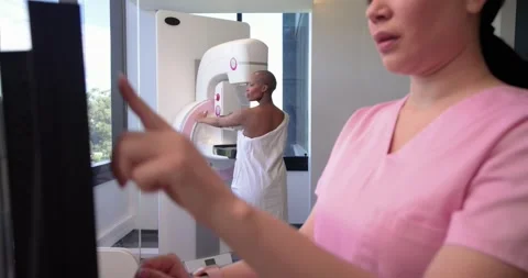 Female patient in gown holding mammogram at clinic while female tech tapping Stock Footage 339320853