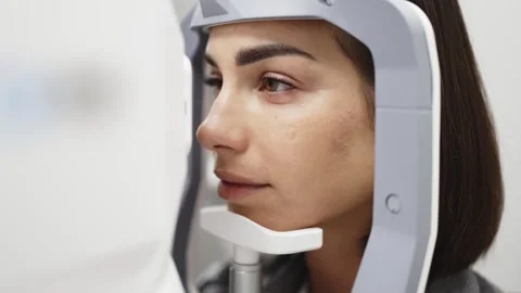 Female patient undergoing optical coherence tomography examination with Stock Footage 337288282