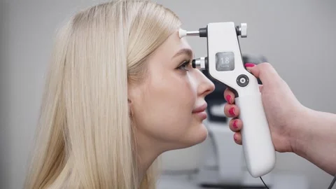 Female patient undergoing tonometry eye examination with a handheld device, Stock Footage 337285897