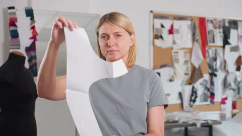 Female Pattern Designer Observing Paper Pattern and Looking at Camera Stock Footage 307136231