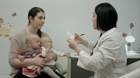 Female pediatrician doctor's explaining something to mother with newborn twins 스톡 동영상 58488352