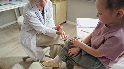 Female Pediatrician Testing Knee Reflex of Girl with Reflex Hammer Stock Footage 337240716