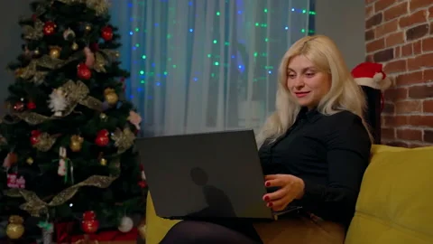 Female person sitting on couch using laptop at home Stock Footage 178987868