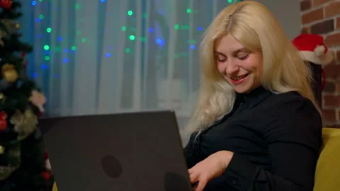 Female person sitting on couch using laptop at home Stock Footage 179006466